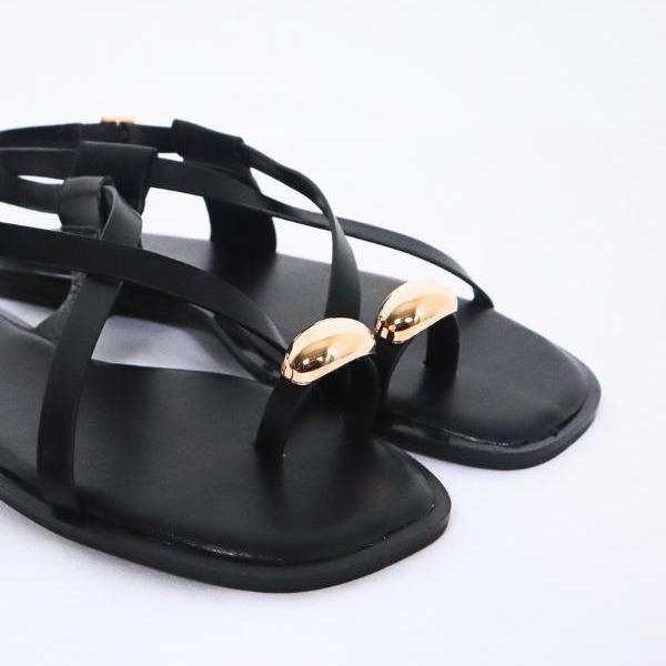 Sandalias planas color negro, detalle del broche dorado